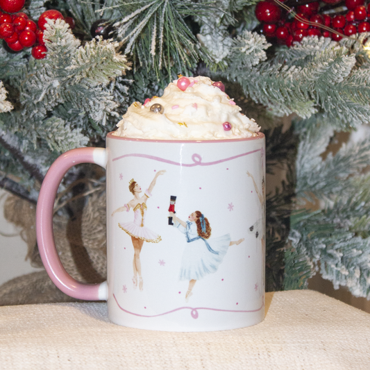 Nutcracker mug with multiple Nutcracker characters including Clara with a Christmas tree and berries in the background.