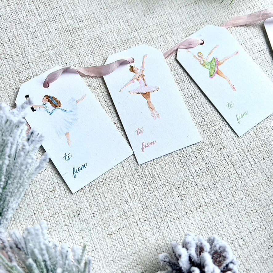 Nutcracker ballet themed gift tags with ballerinas. Greenery in the background on a cloth background