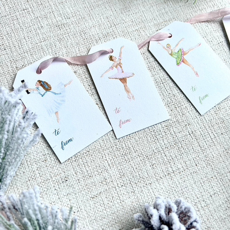 Nutcracker ballet themed gift tags with ballerinas. Greenery in the background on a cloth background