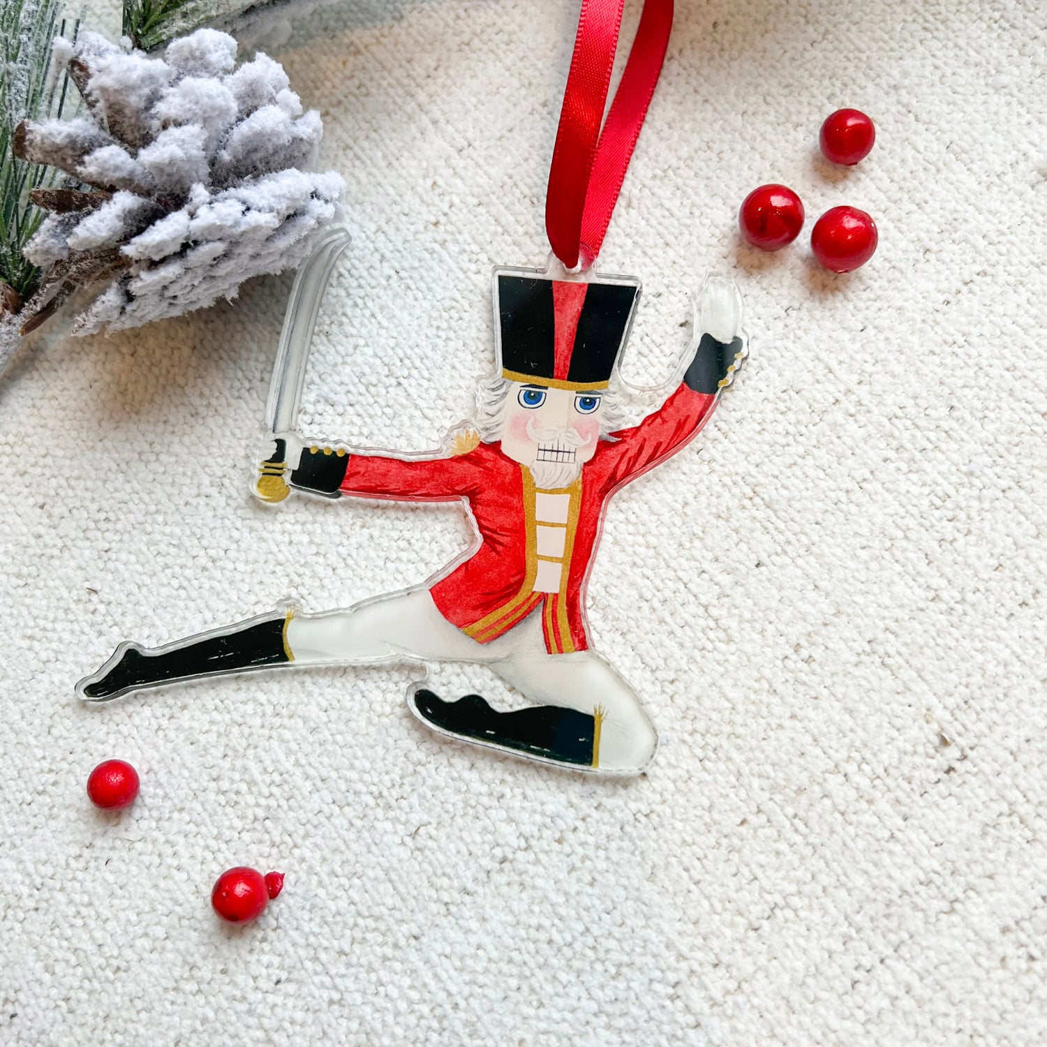 Nutcracker Prince ornament with a red ribbon. Cranberries and a pine cone in the background.