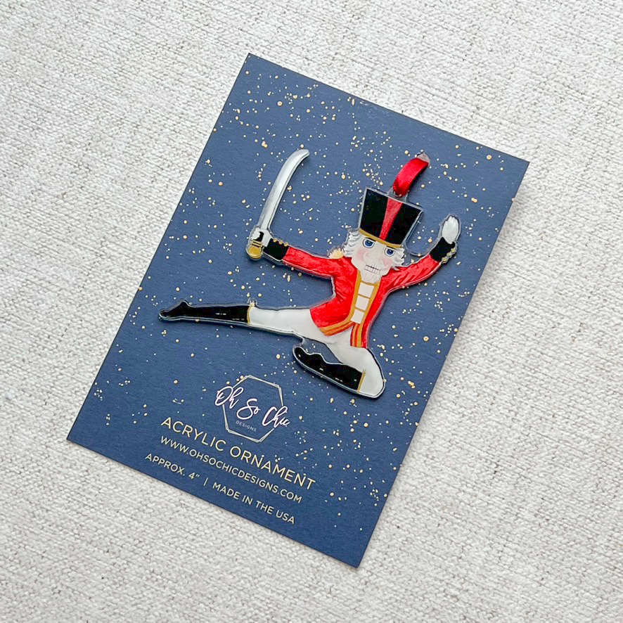 Nutcracker prince ornament on a card backer with a red ribbon